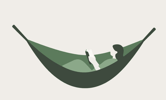 A flat illustration of a person lying back and reading a book in a hammock made from one large leaf slung between two stems.